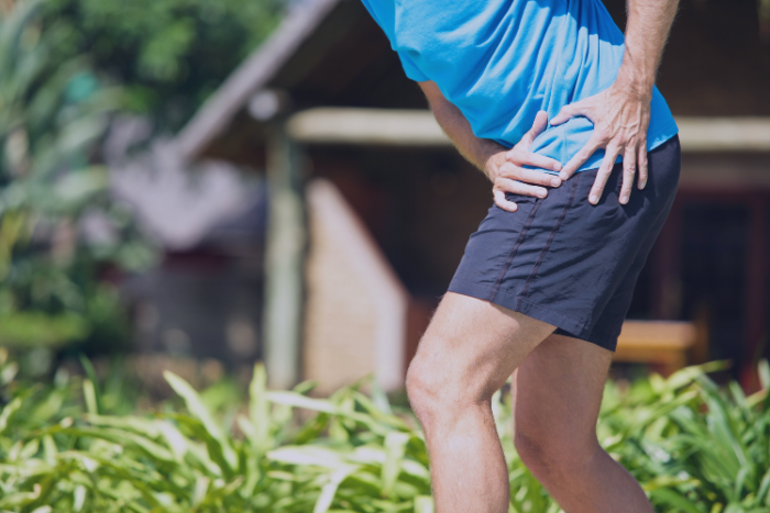 Long-term Injuries Diagnosis and Treatment Man in shorts holding hip in pain